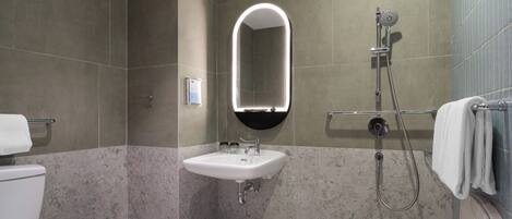 Baño con inodoro, lavamanos, ducha y espejo.
