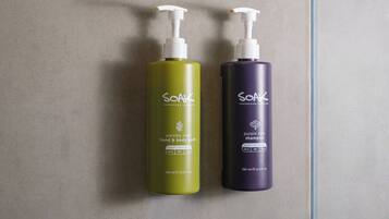 Two bottles of Soak Superfood Shampoo, one green and one purple, with pumps and labels indicating they are for hand and body wash.