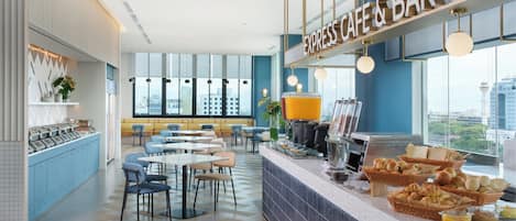 A modern cafe with a bar, seating area, and buffet with breakfast items.