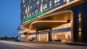 A modern hotel with a prominent 'Holiday Inn' sign, large glass entrance, and a curved awning. - Holiday Inn Quanzhou Jinjiang Airport by IHG (Quanzhou)