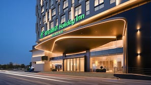 Un hôtel moderne, reconnaissable à son grand panneau « Holiday Inn », à son entrée en verre et à son auvent incurvé.