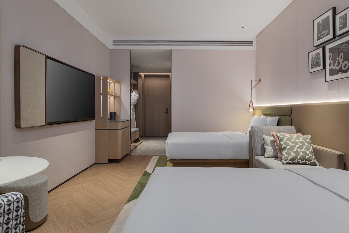 A hotel room with a bed, a desk, a television, and a bathroom.