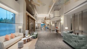 A spacious hotel lobby with a central spiral staircase, a reception desk, and a seating area with a sofa and coffee table. - Holiday Inn Quanzhou Jinjiang Airport by IHG (Quanzhou)
