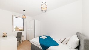 Een slaapkamer met een bed, bureau, stoel, kledingkast en raam met uitzicht.