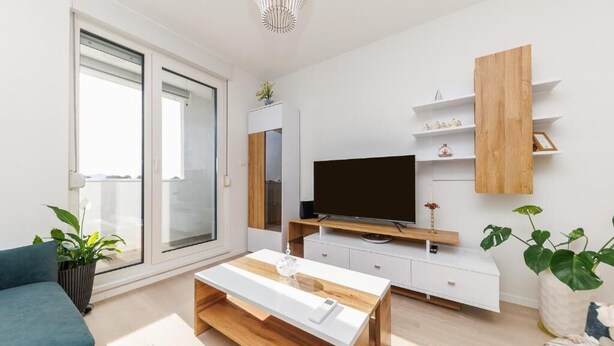 Een moderne woonkamer met een bank, een salontafel, een televisie en een houten kast.