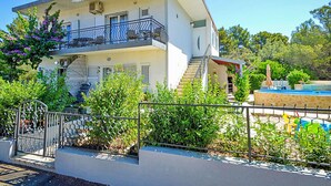 Ein zweistöckiges Gebäude mit Balkon, Schwimmbad und Garten.