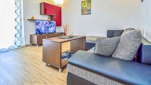 Ein modernes Wohnzimmer mit einer Couch, einem Fernseher, einem roten Schrank und einer Wand-Klimaanlage.