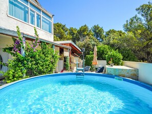A swimming pool with lounge chairs, a covered patio, and lush greenery. - Antonia by Interhome (Brodarica)