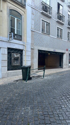 Eine Kopfsteinpflasterstraße mit einem Gebäude, das eine Fassade mit Kacheln und einen Eingang im Erdgeschoss hat.