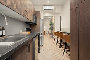 A modern kitchen with a herringbone floor, stainless steel appliances, and wooden cabinetry. - Condado Modern-Cozy 2-Bedroom City & Sea Getaway (San Juan)