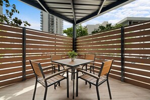 A covered patio with a table and chairs, a potted plant, and a view of buildings. - Condado 5BR Apt| Walk to Beach & Restaurants (San Juan)