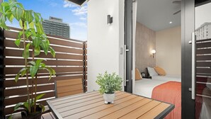 Un balcon avec une table en bois, un pot de fleurs et une vue sur un bâtiment de l’hôtel Marriott.