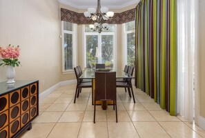Un coin repas comprenant une table en verre, des chaises, un vase avec des fleurs et un meuble décoratif.