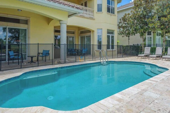 Une piscine avec des chaises longues et un espace patio couvert.