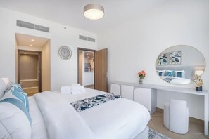 Ein modernes Hotelzimmer mit Bett, Schreibtisch, Spiegel und einer Badezimmertür.