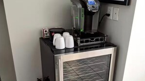 Een kleine keuken met een koffiezetapparaat, een kleine koelkast en een magnetron.