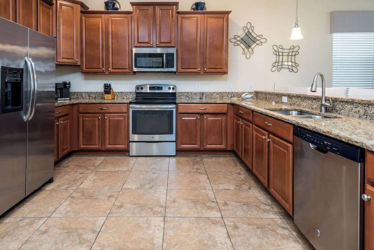 A kitchen with wooden cabinets, a stainless steel refrigerator, a microwave, an oven, and a dishwasher.