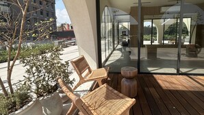 A balcony with wicker furniture, a wooden table, and potted plants. - Modern Executive Loft near Financial District - Fast WiFi, Gym, Parking (Guadalajara)