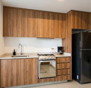 Eine moderne Küche mit Holzausstattung, einem Edelstahlherd und einem schwarzen Kühlschrank.
