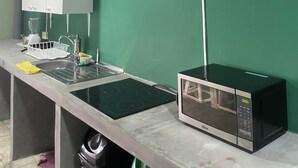 A kitchen with a microwave, sink, and white cabinets. - Hostel YEK (Santa Ana)