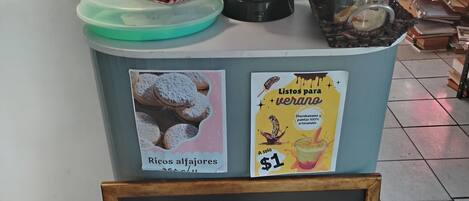 A coffee station with a coffee maker, a bottle of milk, and a sign advertising coffee beans.