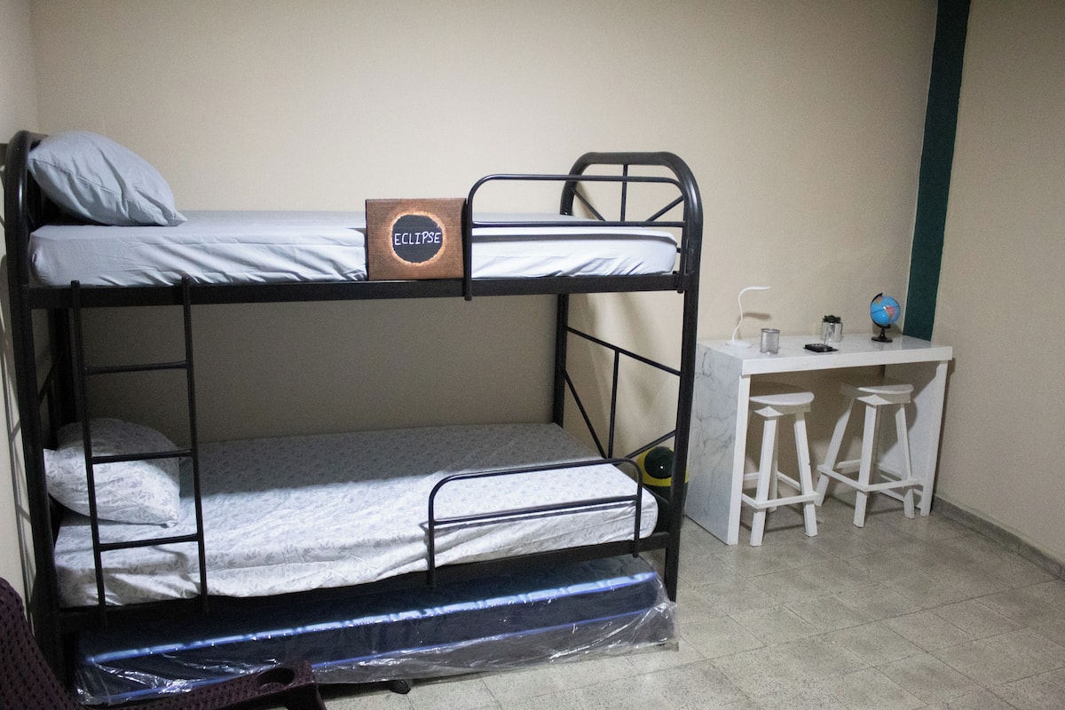 A bunk bed with a label, a desk with two stools, and a globe.