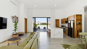 A modern living room with a sofa, a TV, and a potted plant.