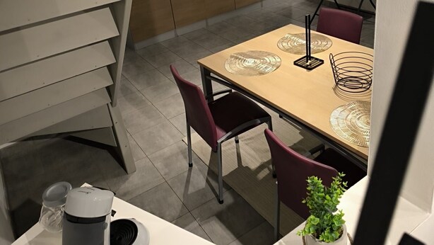 Une cuisine moderne avec un coin repas, un escalier et un tableau blanc fixé au mur.