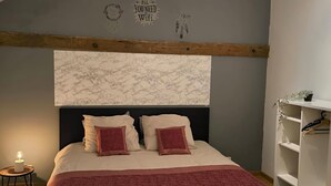 Une chambre à coucher comprenant un lit, une table de chevet, une étagère fixée au mur et un ventilateur de plafond.