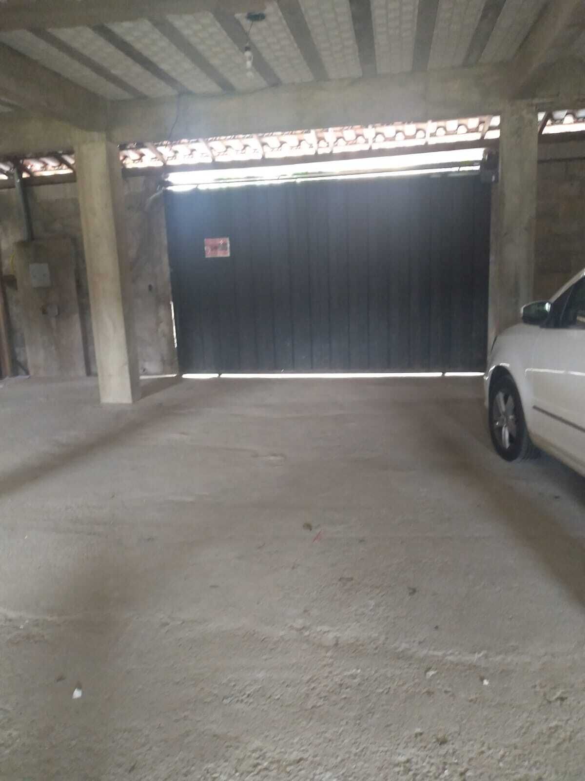 An indoor parking area with a concrete floor and a large, dark-colored garage door.