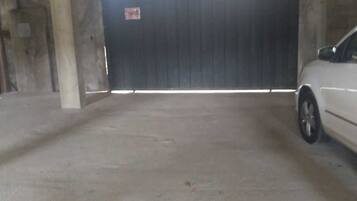 An indoor parking area with a concrete floor and a large, dark-colored garage door.