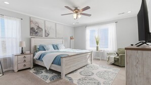 Ein Schlafzimmer mit Bett, Nachttisch, Lampe, Deckenventilator und Fernseher.