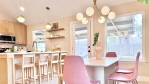 Una cocina moderna con armarios de madera, una isla central y sillas rosadas.