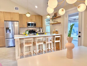 Une cuisine moderne dotée d’appareils électroménagers en acier inoxydable, de meubles en bois et d’un îlot central avec des tabourets de bar.