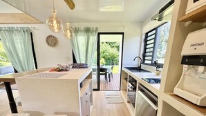 A modern kitchen with a central island, a sink, a coffee machine, and a dining area with chairs. - Villa Vaimoeani + bungalow  - pool - serenity in Moorea, Haapiti - 8 pers (Haapiti)