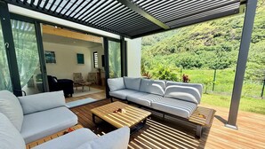 A modern outdoor living area with a sofa, chairs, and a wooden table. - Villa Vaimoeani + bungalow  - pool - serenity in Moorea, Haapiti - 8 pers (Haapiti)
