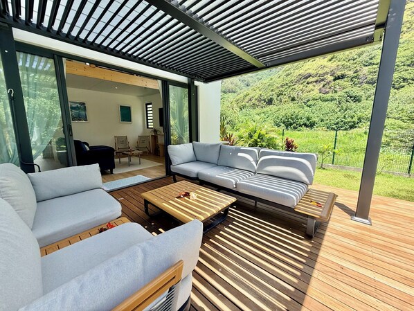 Un espacio exterior moderno con sofá, sillones y una mesa de madera.