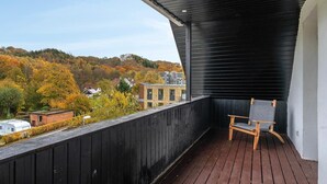 A balcony with a wooden floor, a chair, and a view of houses and trees.