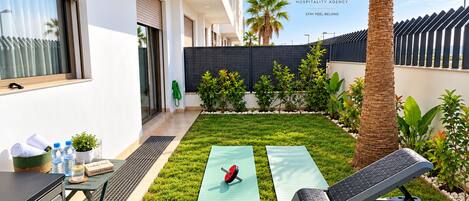 A modern outdoor area with a yoga mat, exercise equipment, and a water bottle on a table.