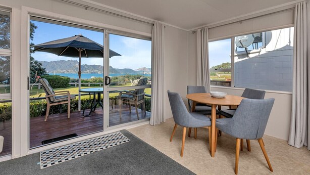 Ein moderner Essbereich mit Tisch und Stühlen, Blick ins Freie und einer Glasschiebetür zu einer Terrasse.