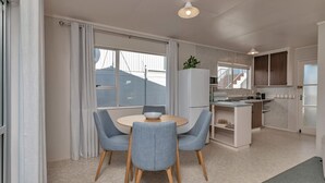 Eine moderne Küche mit Kühlschrank, Herd und Essbereich mit Stühlen und Tisch.