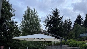 A patio area with outdoor furniture, a large umbrella, and a stone wall.