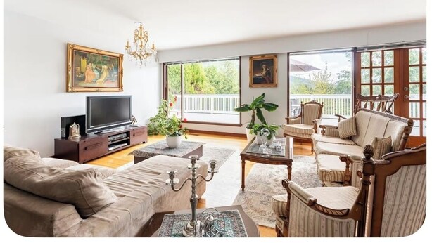 A living room with a sofa, a television, a chandelier, and a balcony with a view. - Entire Peaceful 3BR Guest Suite Upper Level West Vancouver: WiFi & Parking (West Vancouver)