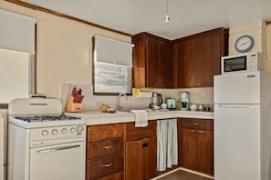 A compact kitchen with wooden cabinets, a stove, a microwave, and a refrigerator. - Treetop Annex, Near Village w/ Forest Views (Big Bear Lake)