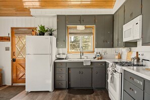 A kitchen with a refrigerator, sink, stove, and cabinets. - Lark Lookout: Serene Surroundings on Huge Private Lot! Hot Tub & Walk to Lake! (Big Bear Lake)