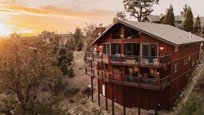 A multi-story wooden cabin with balconies, surrounded by trees and a rocky landscape. - Cliffhanger Cabin, Near Snow Summit w/ Hot Tub (Big Bear Lake)