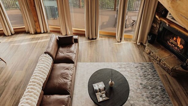 A cozy room with a leather sofa, a round coffee table, and a fireplace. - Cliffhanger Cabin, Near Snow Summit w/ Hot Tub (Big Bear Lake)
