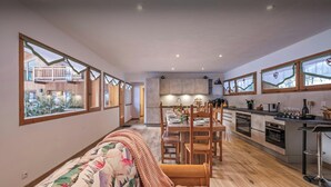 Una cucina moderna con mobili in legno, un'area pranzo con tavolo e sedie in legno, e ampie finestre con tende.