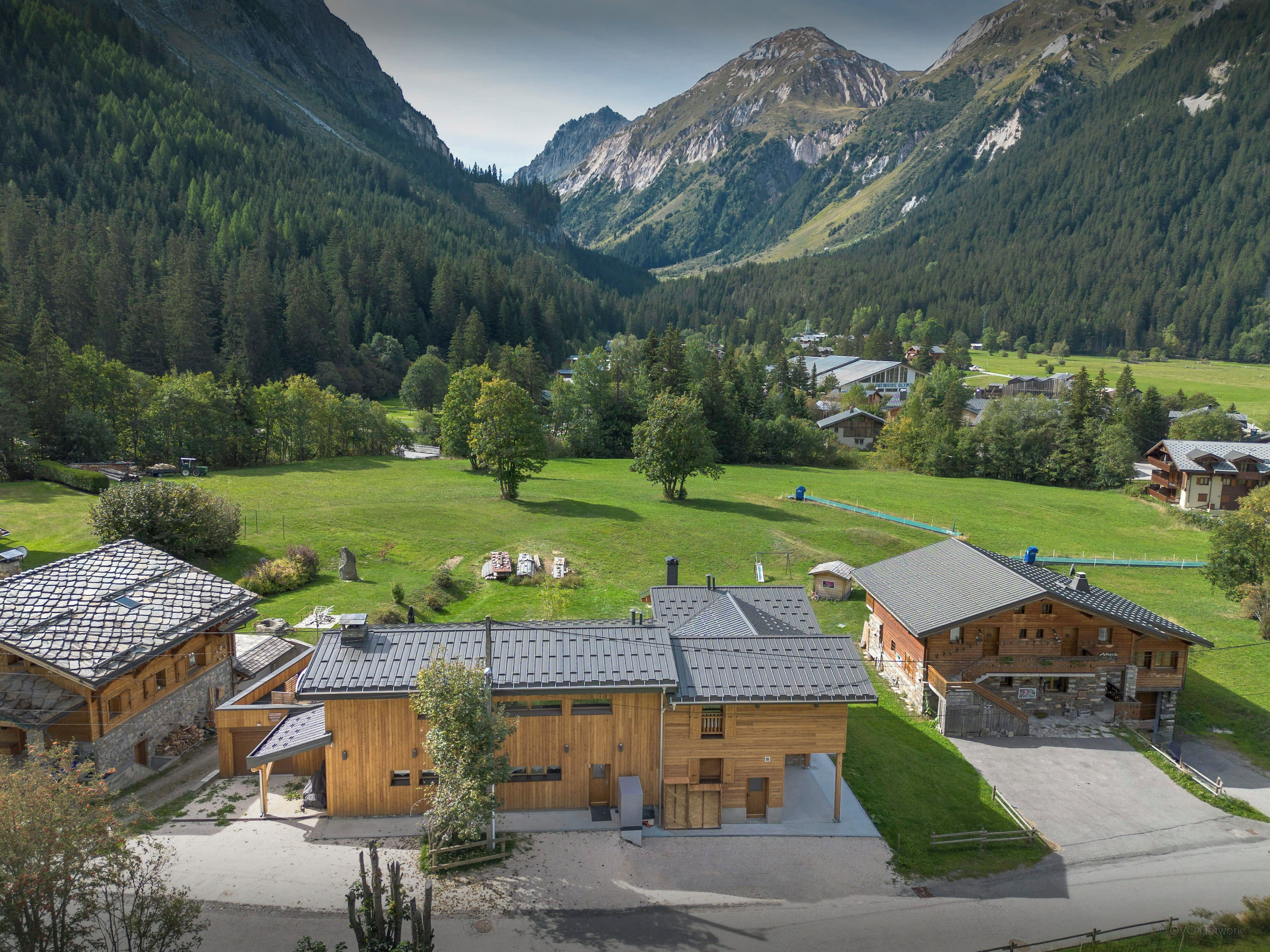 A mountain lodge with a stone facade, wooden exterior, and a view of the surrounding forest and mountains.