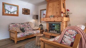 Un soggiorno accogliente con un camino in legno, un divano, una poltrona e un tavolino.